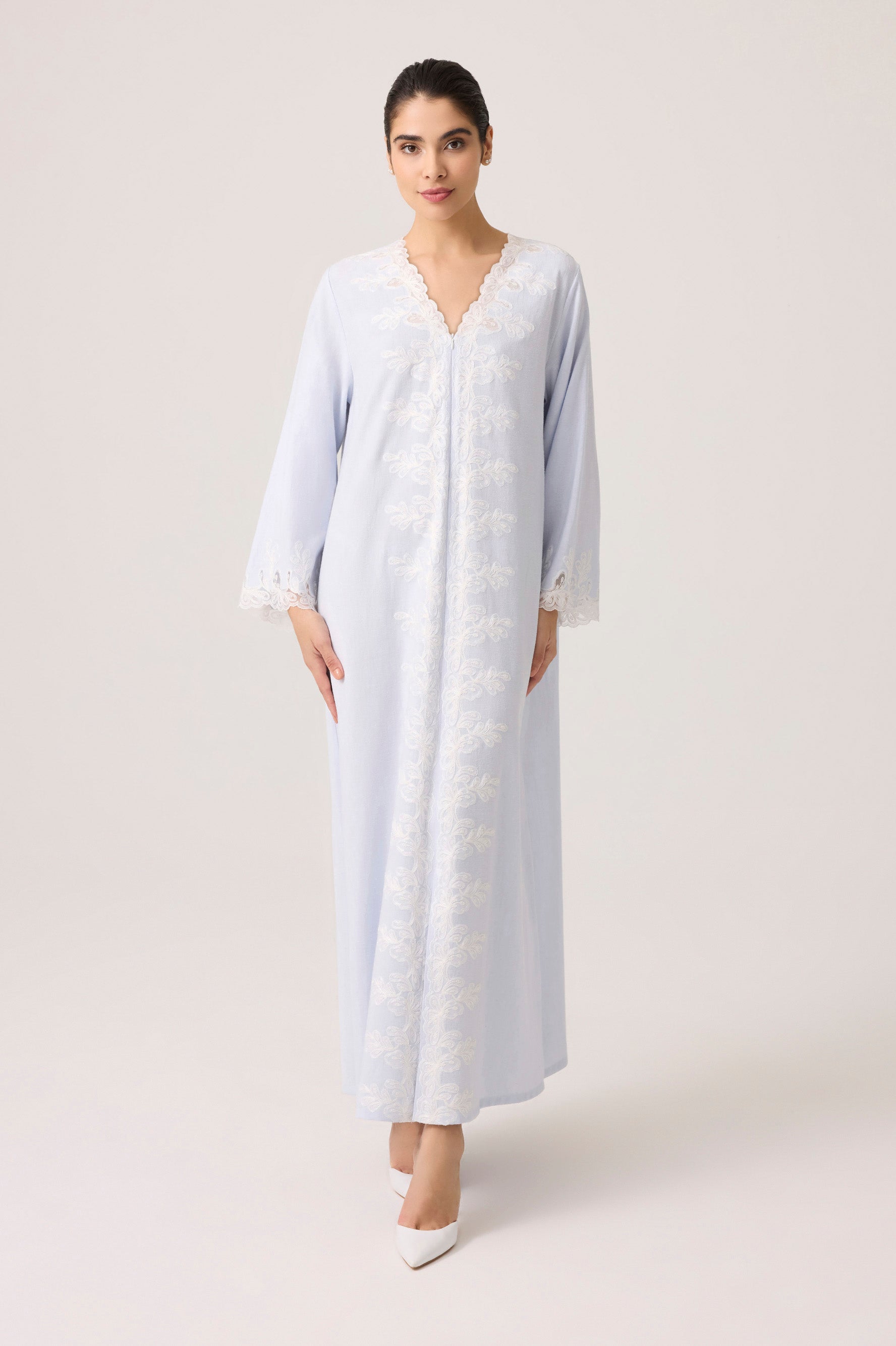 Woman wearing a light blue dress with white patterns on a plain background