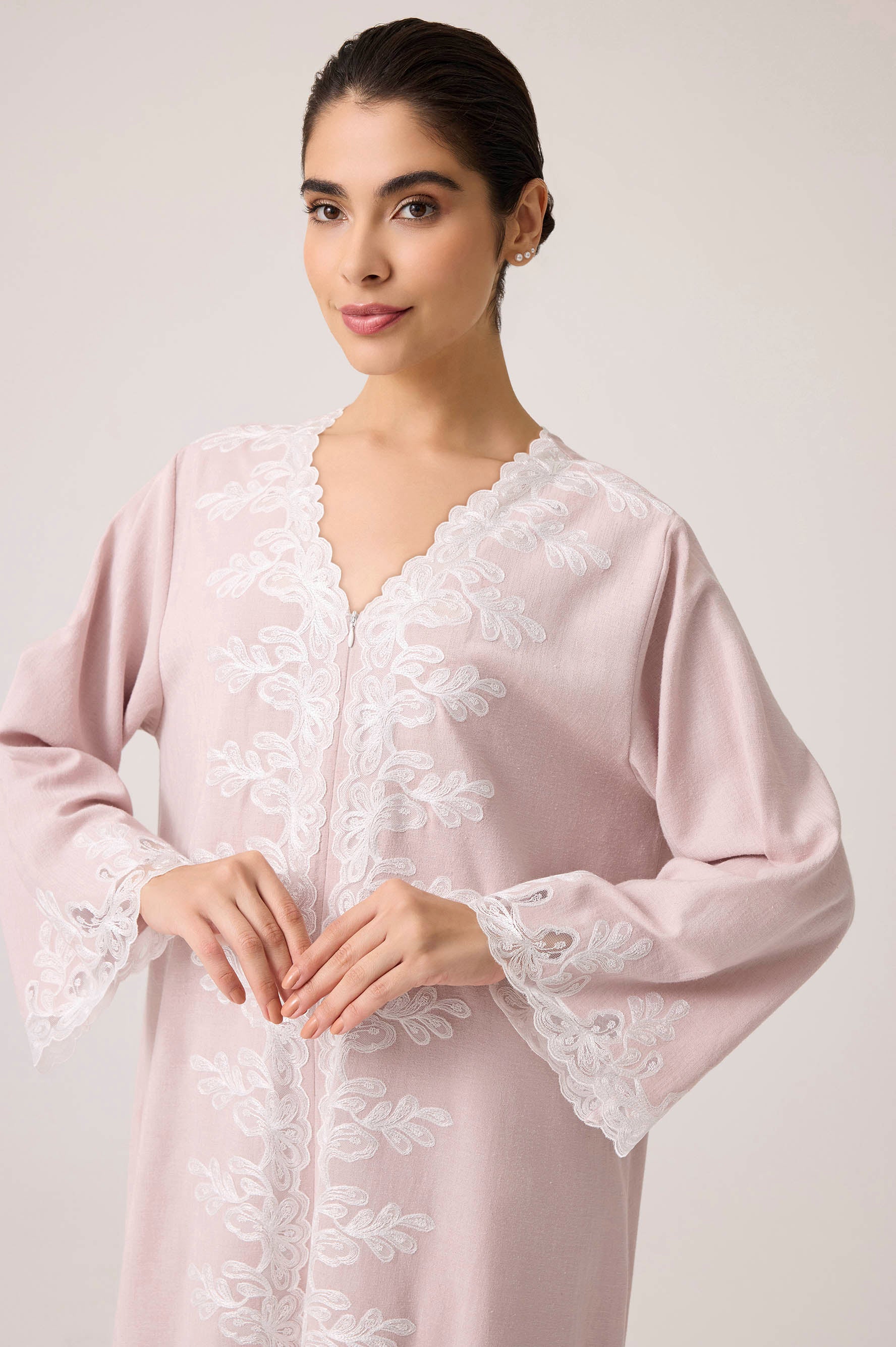 Woman wearing a powder dress with lace details on a plain background
