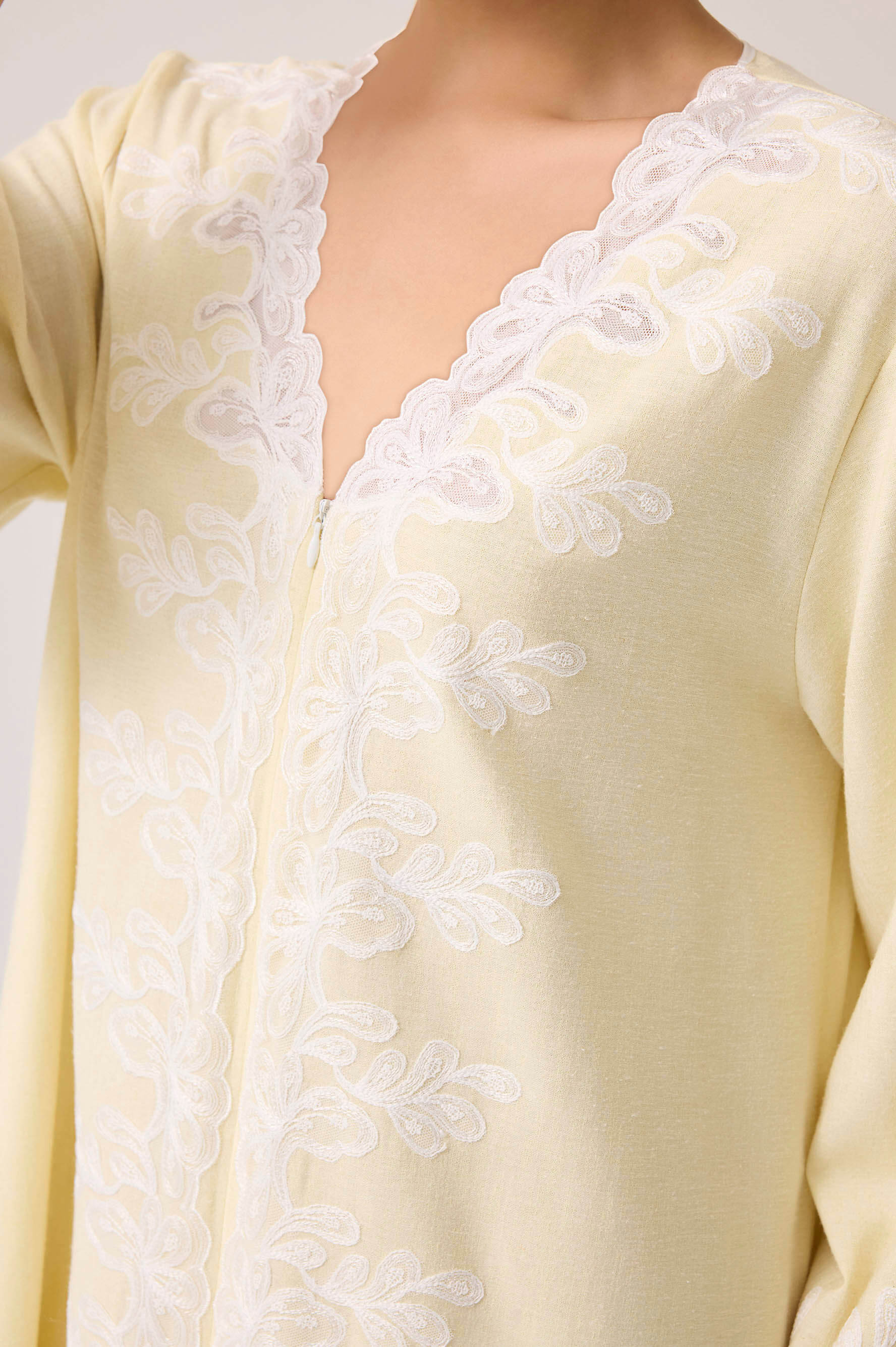 Light yellow dress with white lace details on a plain background