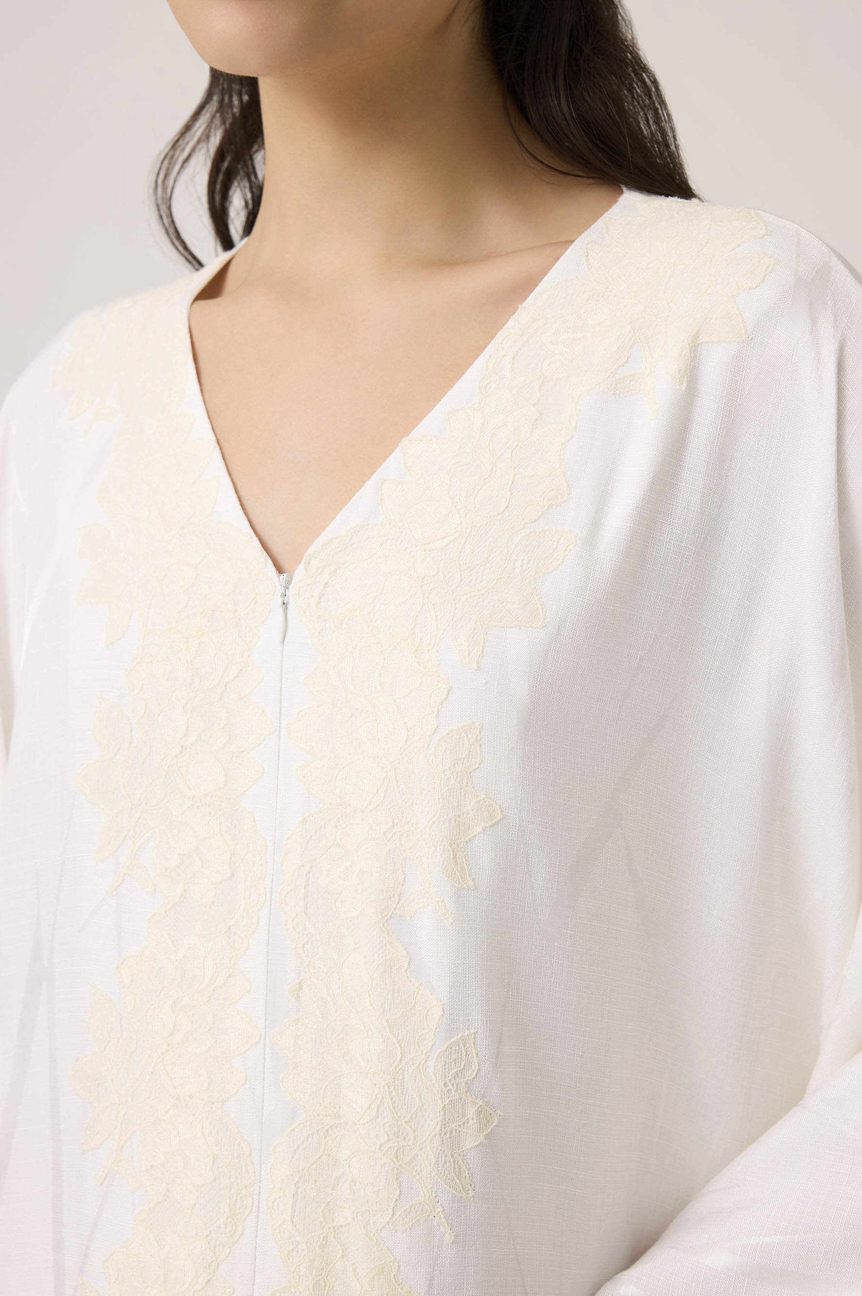 Close-up of a white garment with a subtle pattern on a plain background