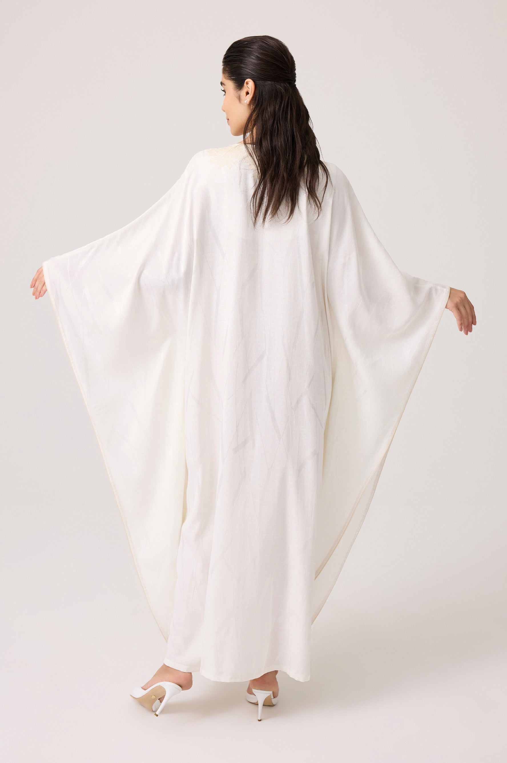 Woman wearing a white flowing garment against a plain background