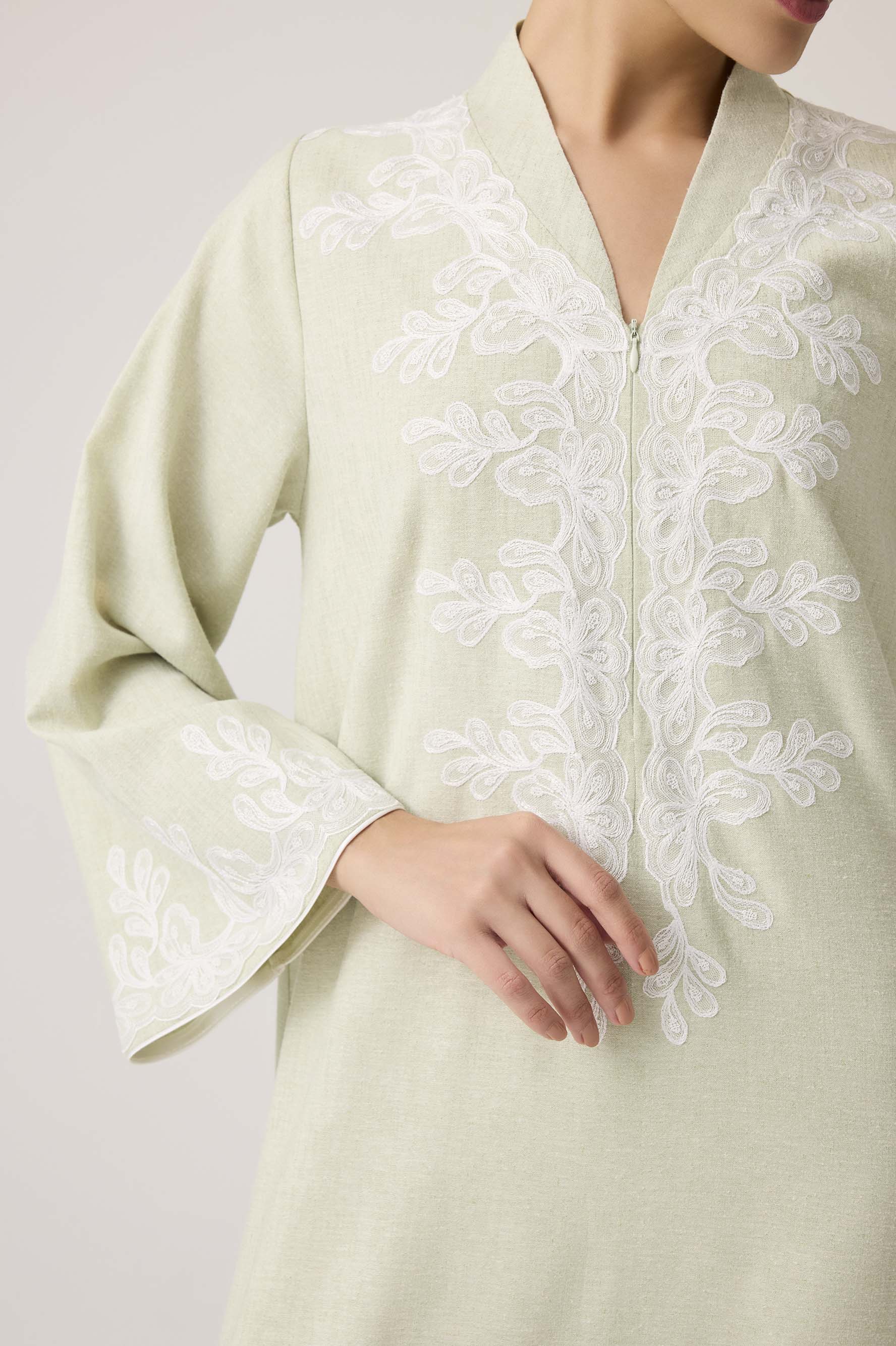 Light green dress with white lace detailing on a plain background