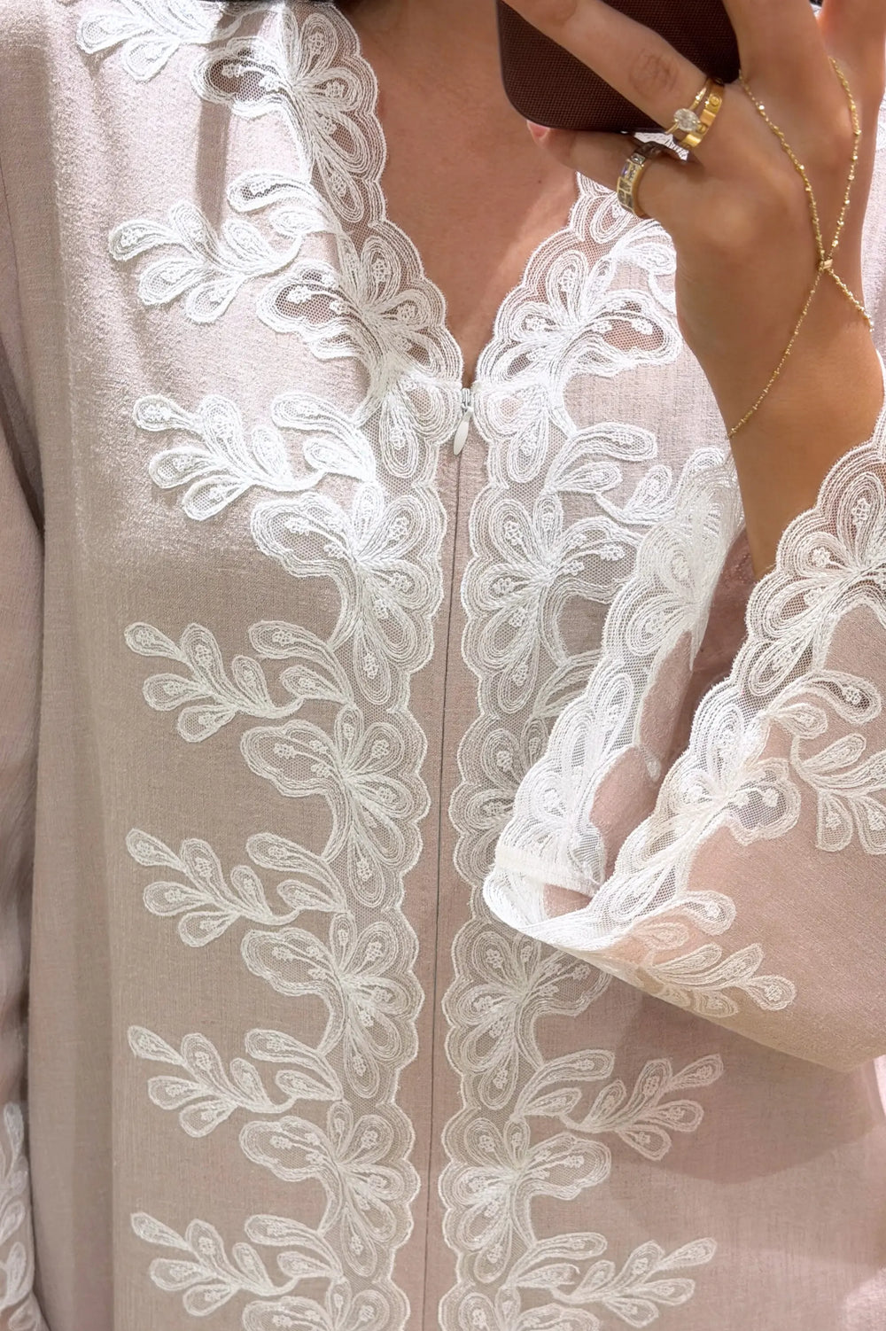 Close-up of a beige dress with intricate white lace detailing