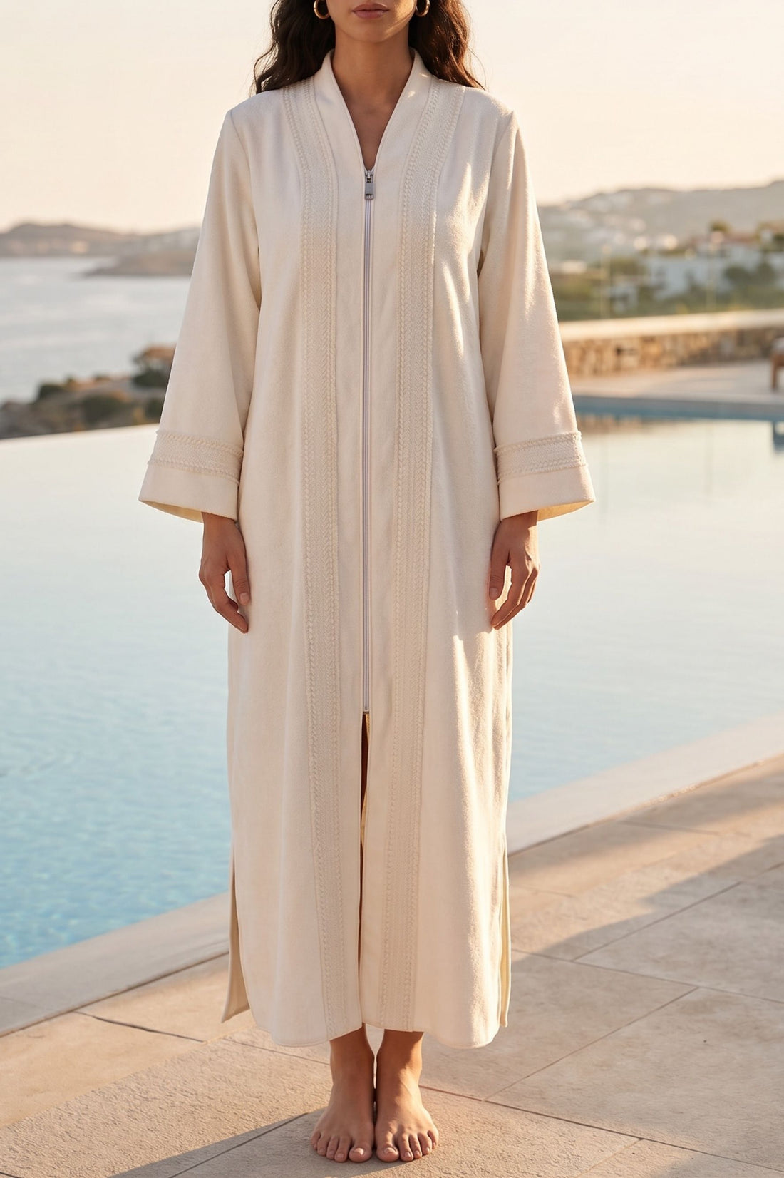 Women wearing a long, light-colored bathrobe by a poolside with a scenic background
