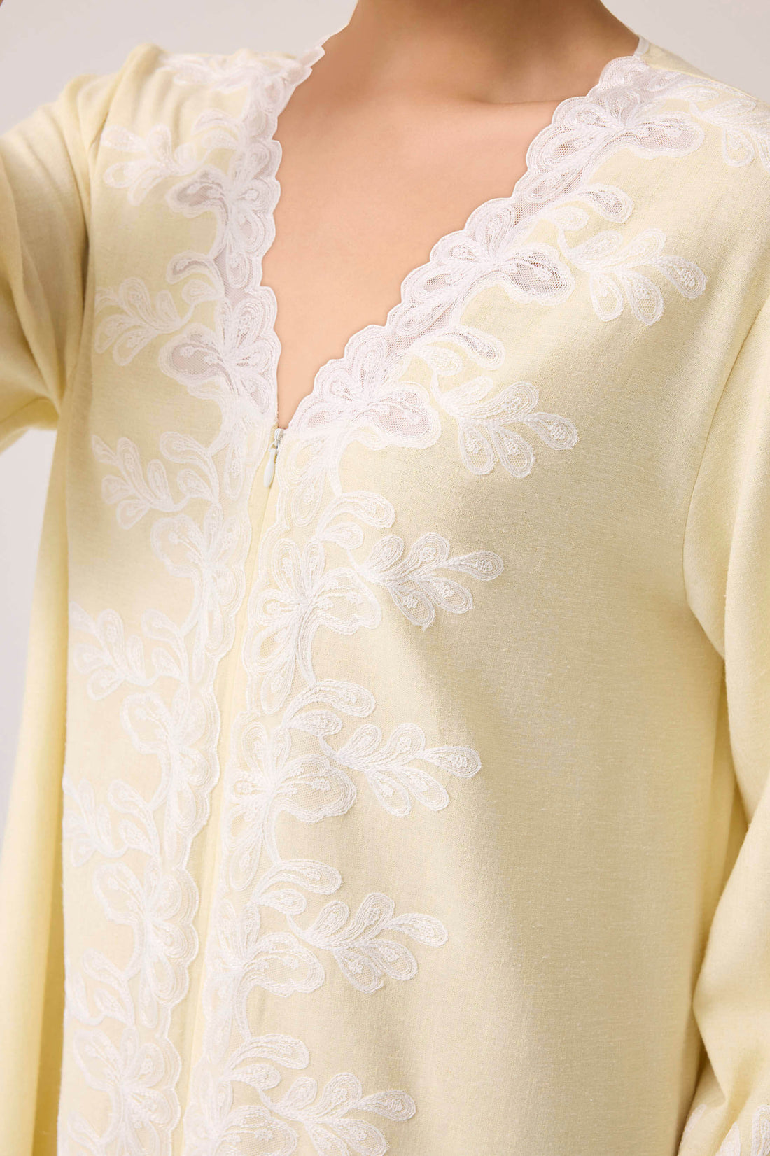 Light yellow dress with white lace details on a plain background