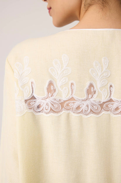 Close-up of a beige garment with intricate white lace detailing on a plain background