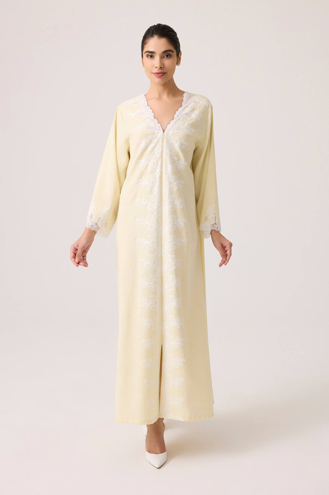 Woman wearing a long, light-colored dress with a subtle pattern on a white background