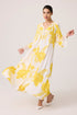 Woman wearing a white dress with yellow floral patterns on a plain background