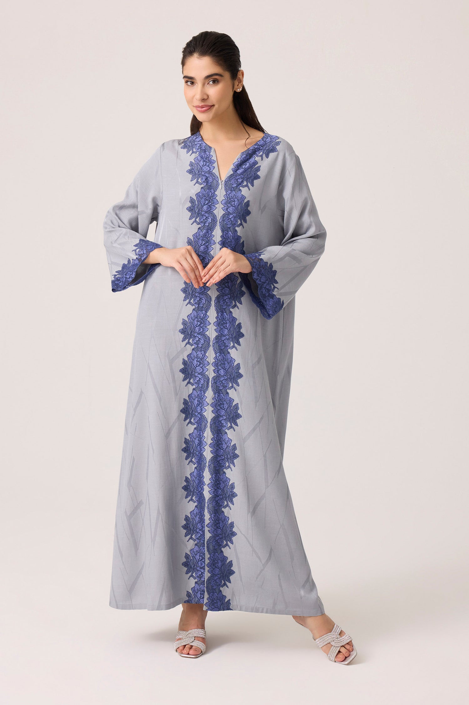 Woman wearing a gray dress with blue lace details on a white background
