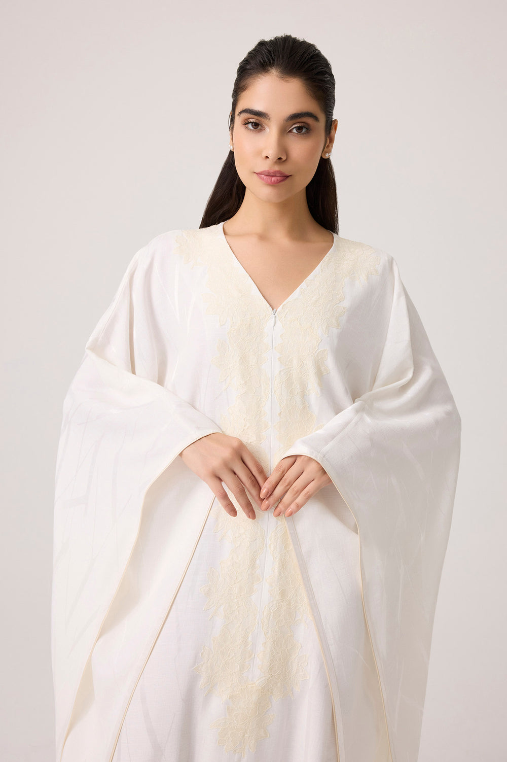 Woman wearing a white shawl against a plain background