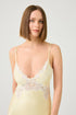 Woman wearing a light yellow lace nightgown against a plain background