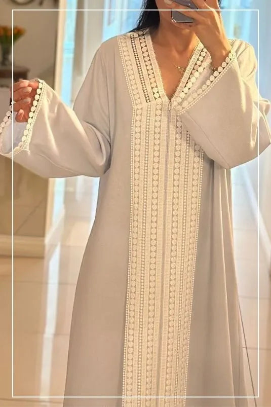 Woman wearing a light-colored dress with lace details in a softly blurred indoor setting.